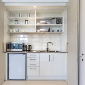 Kitchenette is the diminutive term for kitchen and that accurately suggests a smaller and more simplified version of a full-sized kitchen